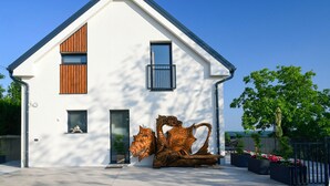 A modern house with a sloped roof, a wooden window, and a metal balcony.