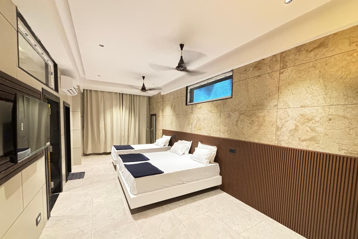 Une chambre d’hôtel moderne avec un grand lit, un téléviseur fixé au mur et un ventilateur de plafond.