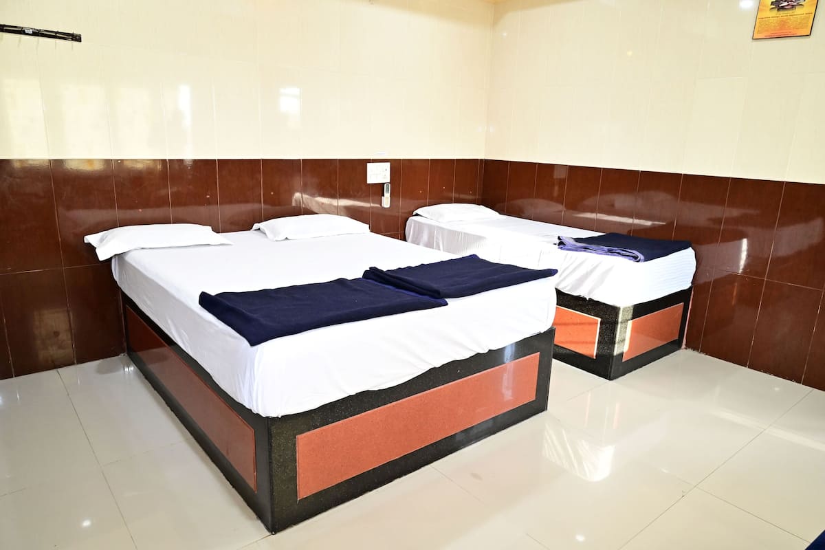 Une chambre d’hôtel avec deux lits, chacun étant équipé de draps blancs et d’une couverture bleu foncé.