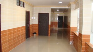 A corridor with tiled walls and a shiny floor, leading to a door at the end. - Sreeniketanam Lodge (Mantralayam)