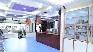 A reception area with a marble counter, glass display cabinets, and a blue floor. - Sreeniketanam Lodge (Mantralayam)