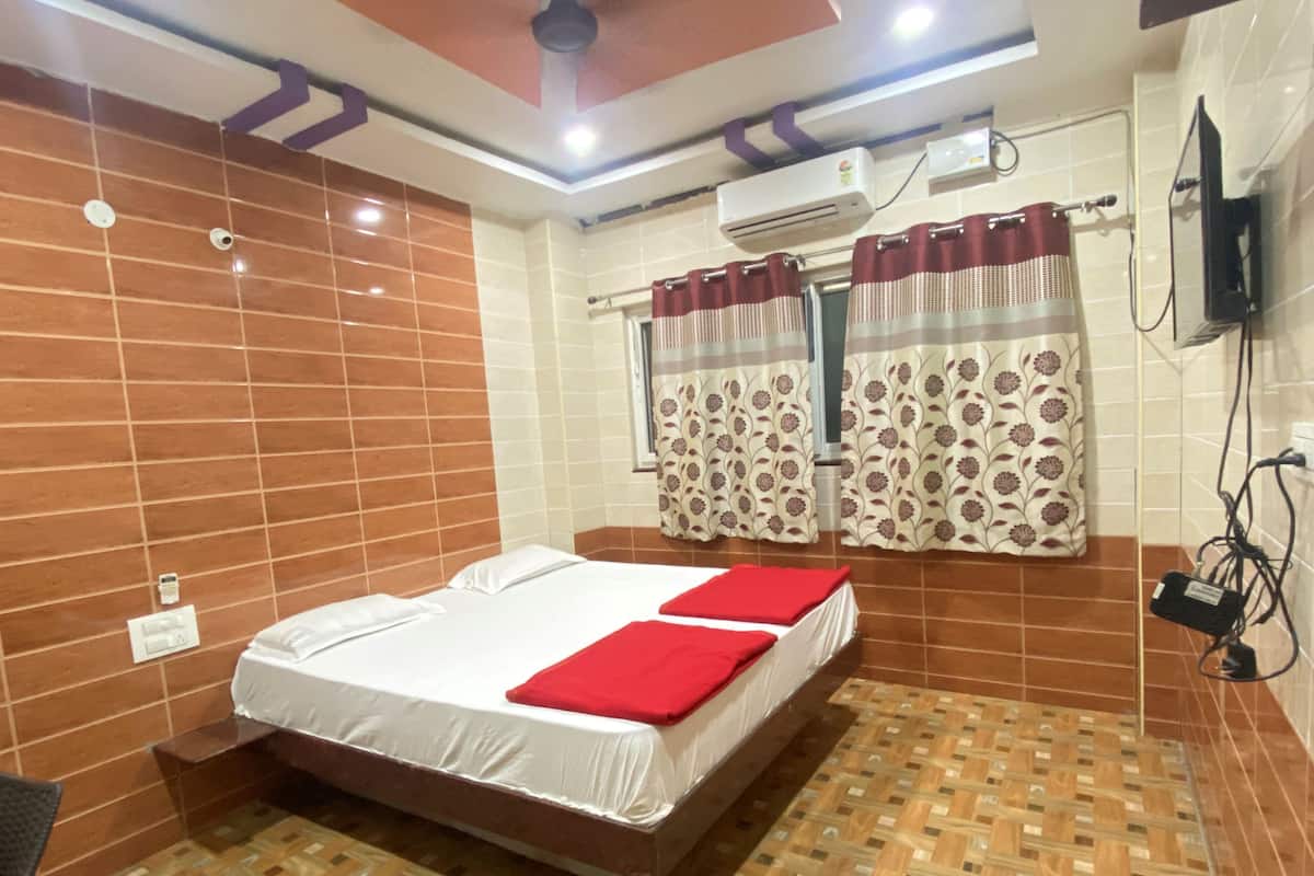Une chambre d’hôtel équipée d’un lit, d’un ventilateur de plafond, d’un climatiseur et d’un téléviseur fixé au mur.