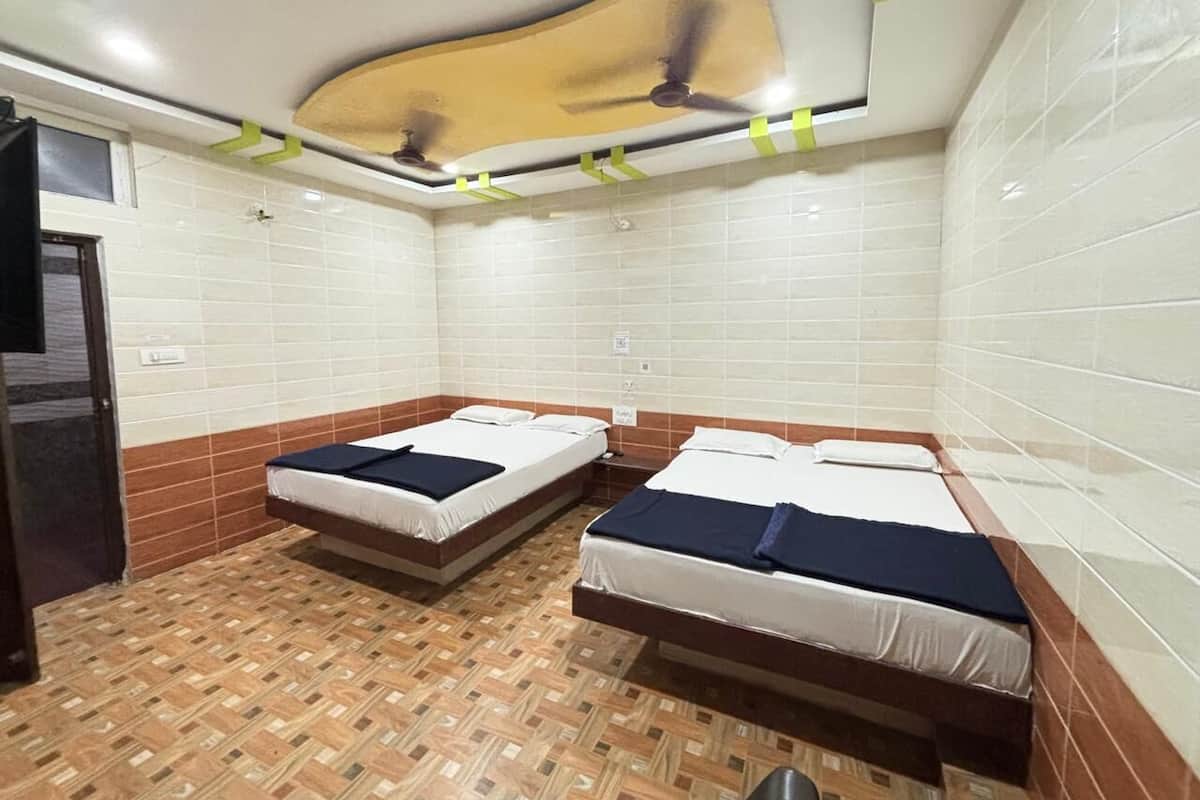 Une chambre avec deux lits, un ventilateur de plafond et un sol à motifs.