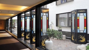 A hotel corridor with black and white doors, a potted plant, and a tiled floor. - The Yun Collection  Yongqingfang  (Guangzhou)