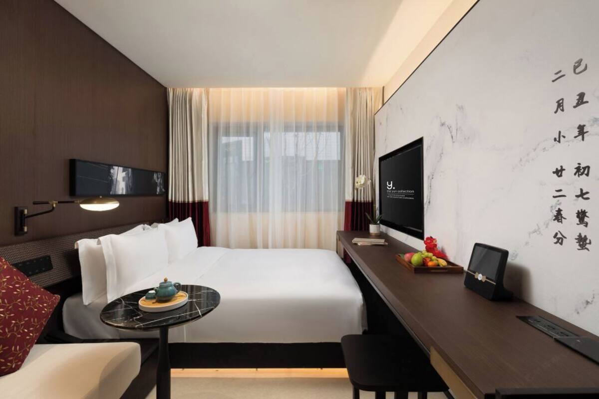 A hotel room with a bed, a desk, a television, and a wall with writing.