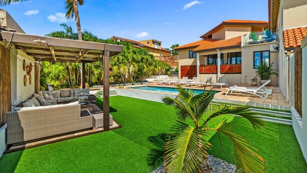 Un jardin avec une piscine, un espace salon extérieur et une terrasse couverte.