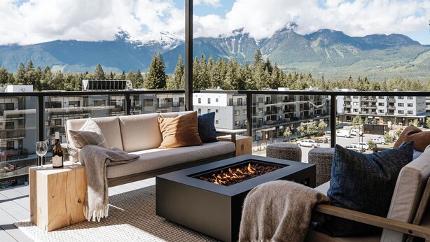 Ein moderner Balkon mit einer Couch, einer Feuerstelle und Bergblick.