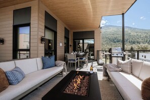 Un espace extérieur moderne aménagé avec des sièges, un foyer, une table à manger et un barbecue.