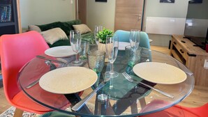 A dining table set with plates, glasses, and cutlery, surrounded by colorful chairs. - New, modern apartment • Comfort - Parking (Sundhoffen)