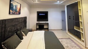 Een moderne slaapkamer met een bed, een televisie, een bureau en een kledingkast.