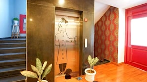 An elevator with a wall mural, a staircase, and a red door. - Ramayan Inn Hotel (Lucknow)