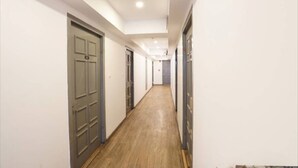 A narrow hallway with doors on both sides, wooden flooring, and white walls. - Ramayan Inn Hotel (Lucknow)