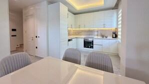 A modern kitchen with white cabinets, a built-in oven, and a countertop with a coffee maker. - SA Apartments! 2bd Duplex next to Cleopatra Beach (Alanya)