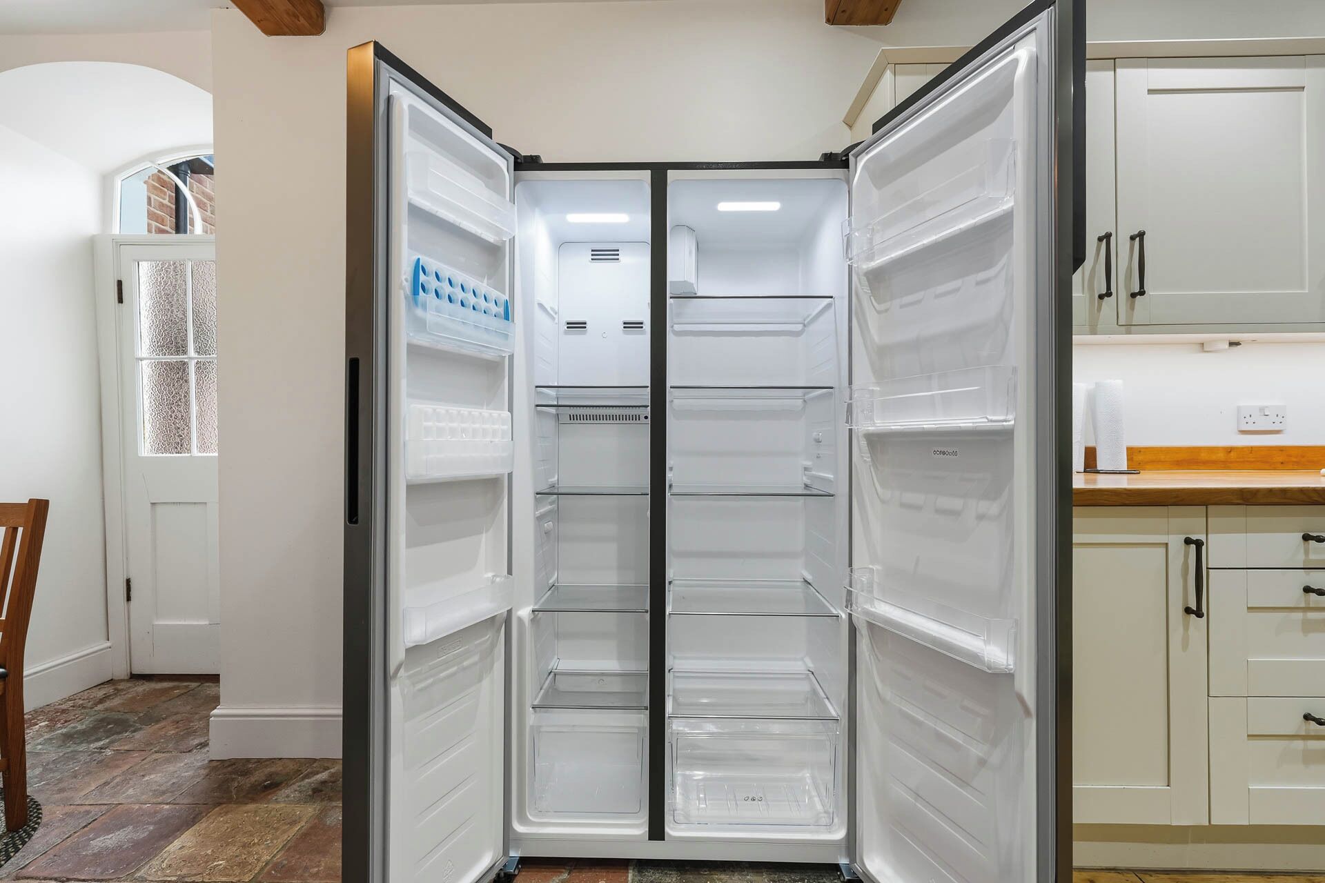 Una cocina moderna con refrigerador empotrado, armarios blancos y piso de madera.
