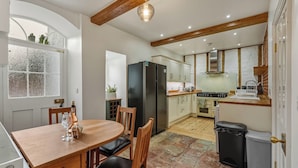 A kitchen with a dining area, featuring a wooden table and chairs, a refrigerator, and a stove.