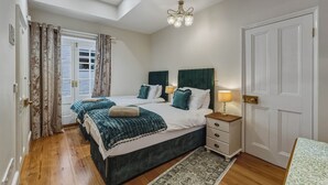 A bedroom with two beds, a chandelier, a nightstand, and a door.