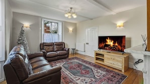 A living room with a fireplace, leather sofa, and a Christmas tree.