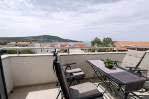 A balcony with a table, chairs, and a potted plant. - Blue Horizon Apartment (Primošten)