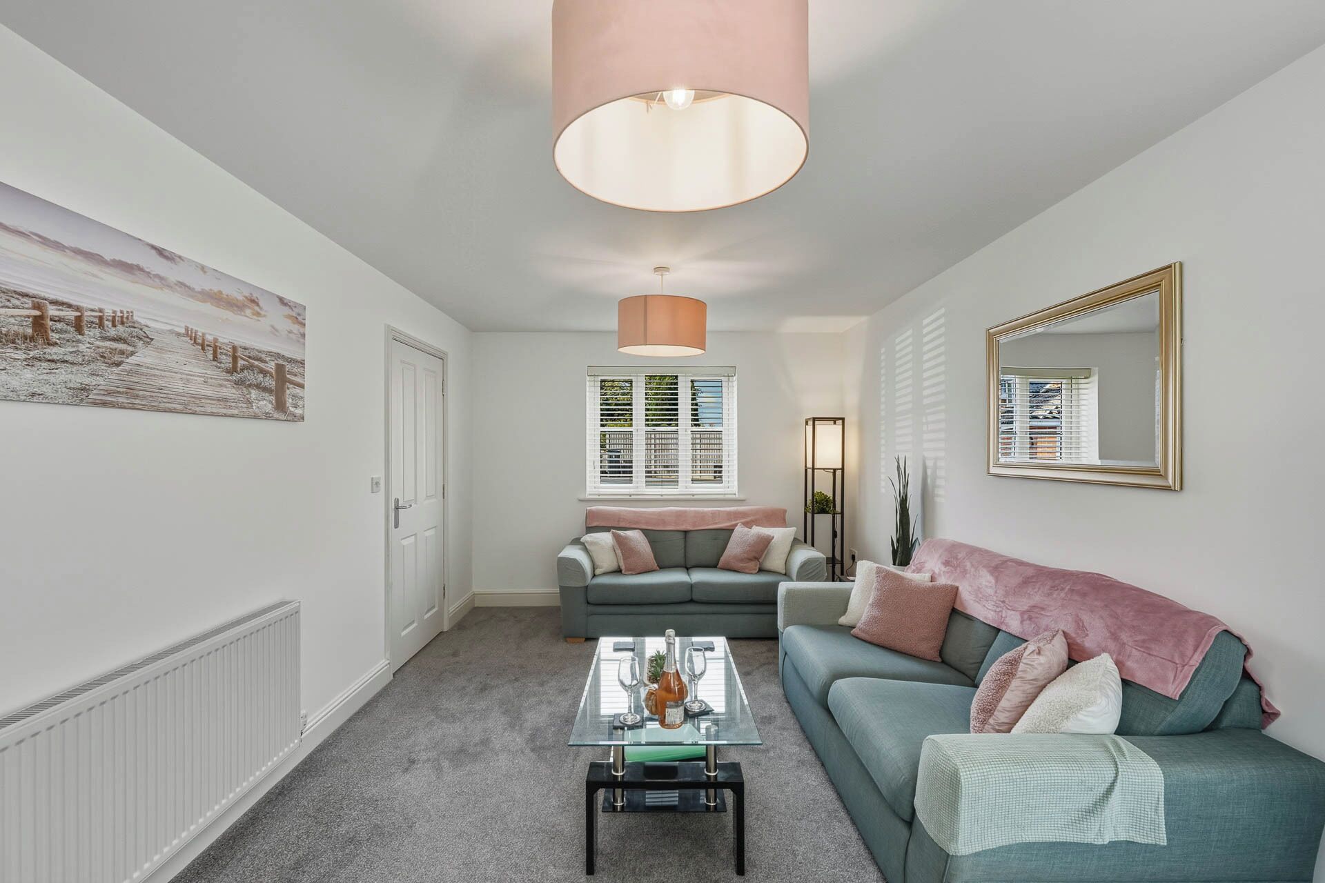 Un salon comprenant un canapé, une table basse, une suspension et un grand miroir.
