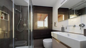 Ein modernes Badezimmer mit einer gläsernen Duschkabine, einer weißen Badewanne und einem großzügigen Waschtisch mit Spiegel.