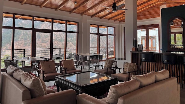 A spacious room with a high ceiling, large windows, and a seating area with sofas and a coffee table. - The Zen Punakha (Punakha)