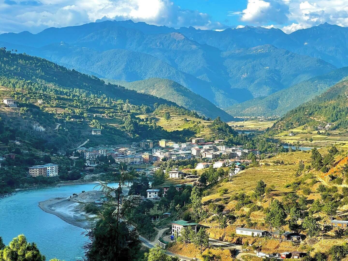 A mountainous landscape with a river, buildings, and a town nestled in the valley.