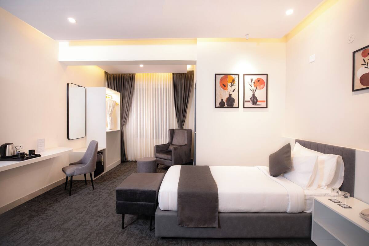 Una habitación de hotel con cama, escritorio, silla y una mesita.