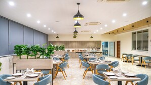 A modern dining area with tables, chairs, and pendant lighting. - U By Z Hotels, Brookefield (Bengaluru)