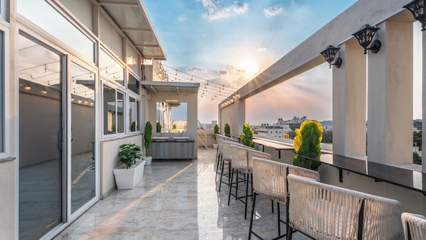 A rooftop terrace with a bar area, potted plants, and a view of the city skyline. - U By Z Hotels, Brookefield (Bengaluru)