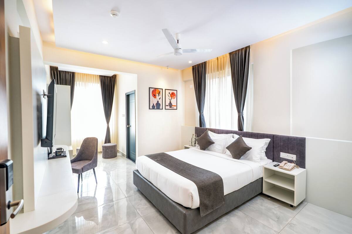 Una habitación de hotel moderna con cama, mesita de noche, silla y televisor.