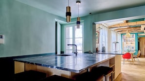 Cozinha moderna com uma ilha grande, banquetas, iluminação pendente e vista para a área de jantar.