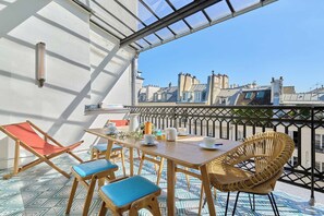 A rooftop terrace with a table, chairs, and a view of city buildings. - Superb Flat With Terrace in the Centre of Paris (Paris)
