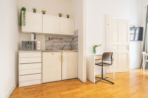 A compact kitchen with white cabinets, a microwave, a sink, and a chair. - Lovely 2BR Near Belvedere Palace (Vienna)