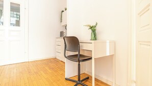 A white desk with a black chair, a small green plant, and a white wall. - Lovely 2BR Near Belvedere Palace (Vienna)