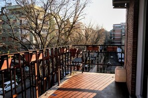 A balcony with a wooden floor, metal railing, and a view of a street with cars and buildings. - Vacation home Eur Laurentina Checchignola. Families, military, (Roma)