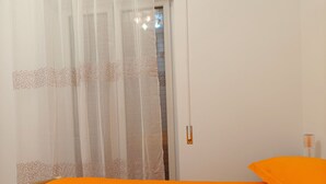 Una stanza con un letto, una porta con tenda e un comodino con lampada.