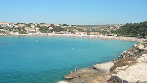 Un pueblo costero con playa, costa rocosa y edificios al fondo.