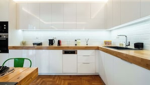 A modern kitchen with white cabinets, a wooden countertop, a dishwasher, and a sink. - MZ Kolonaki (Athina)