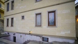 A building with multiple windows, a small entrance, and a light fixture on the ground floor. - nirvana cave house hotel (Nevsehir)
