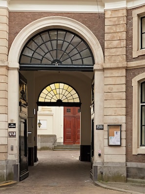 An arched entrance with a brick facade, a wooden door, and a sign indicating parking availability.