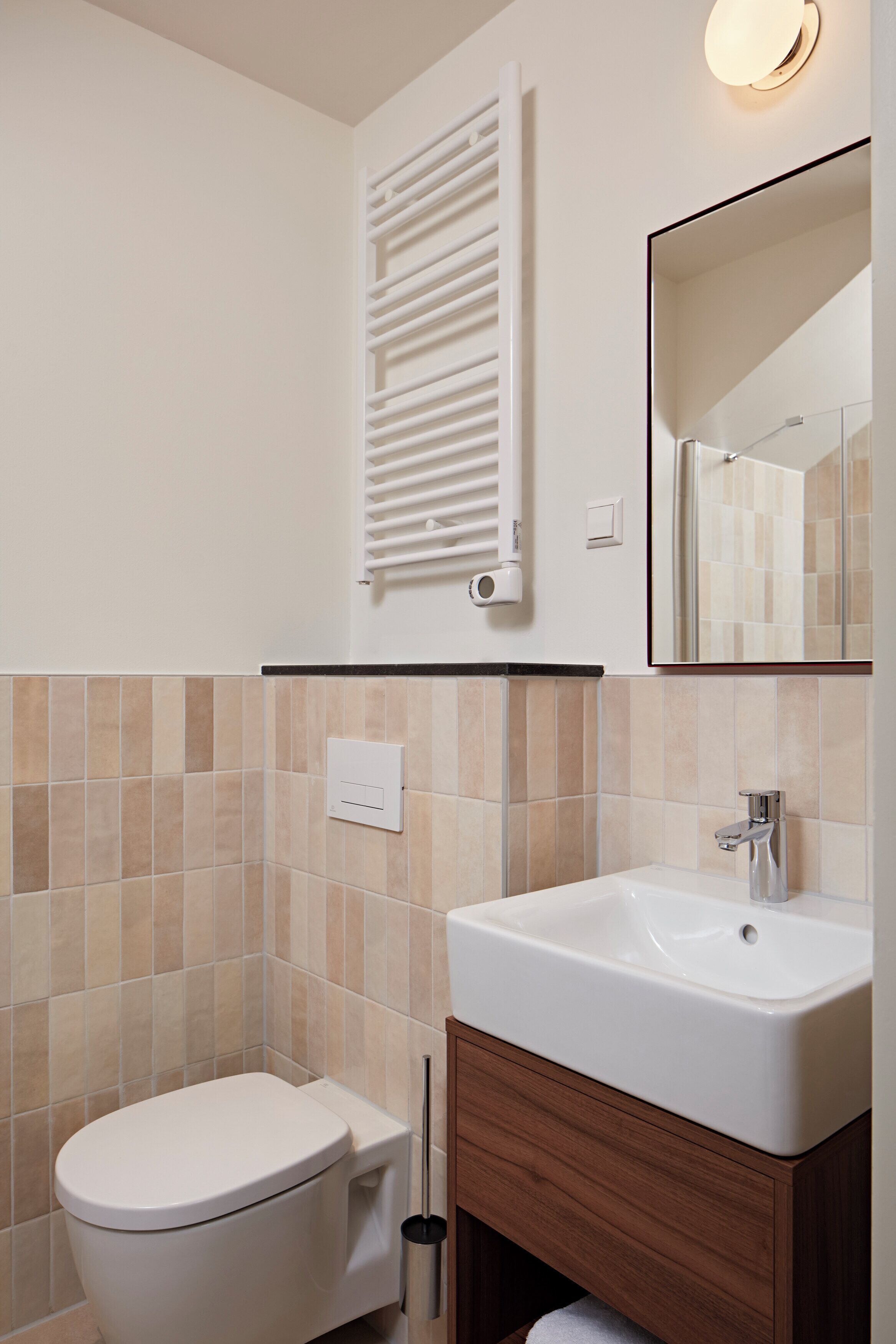 Un baño con inodoro, lavabo, espejo y perchero para toallas.