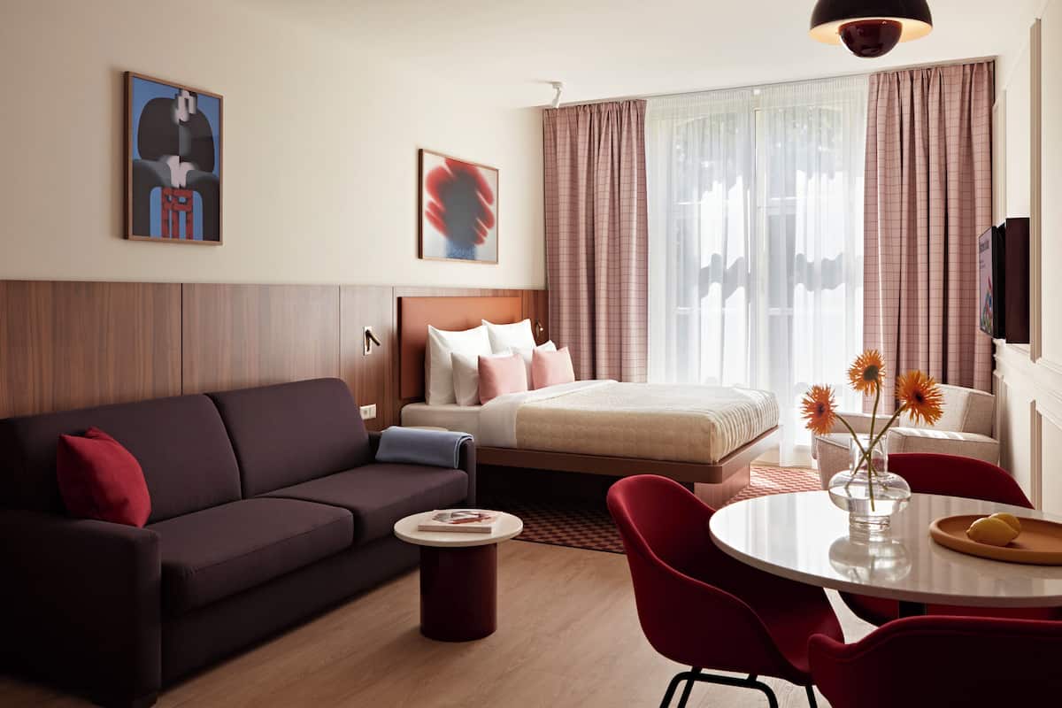Een moderne hotelkamer met een bed, een bank, een eettafel en een televisie.
