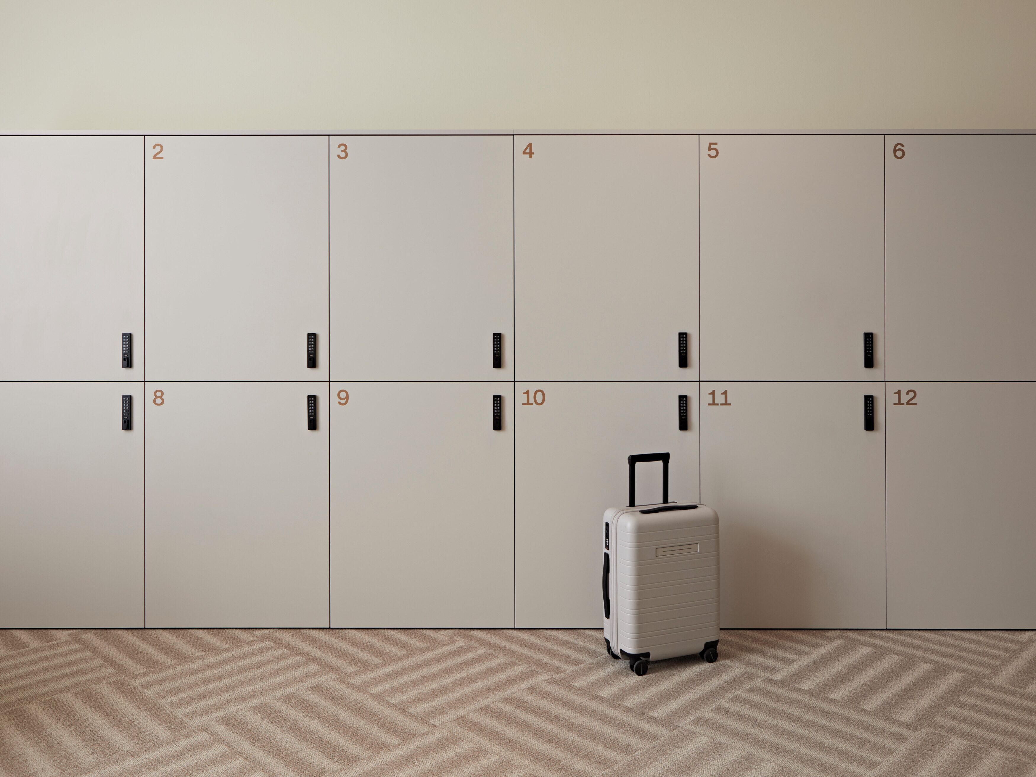 A row of lockers numbered 2 to 12, with a suitcase in front of locker 10.