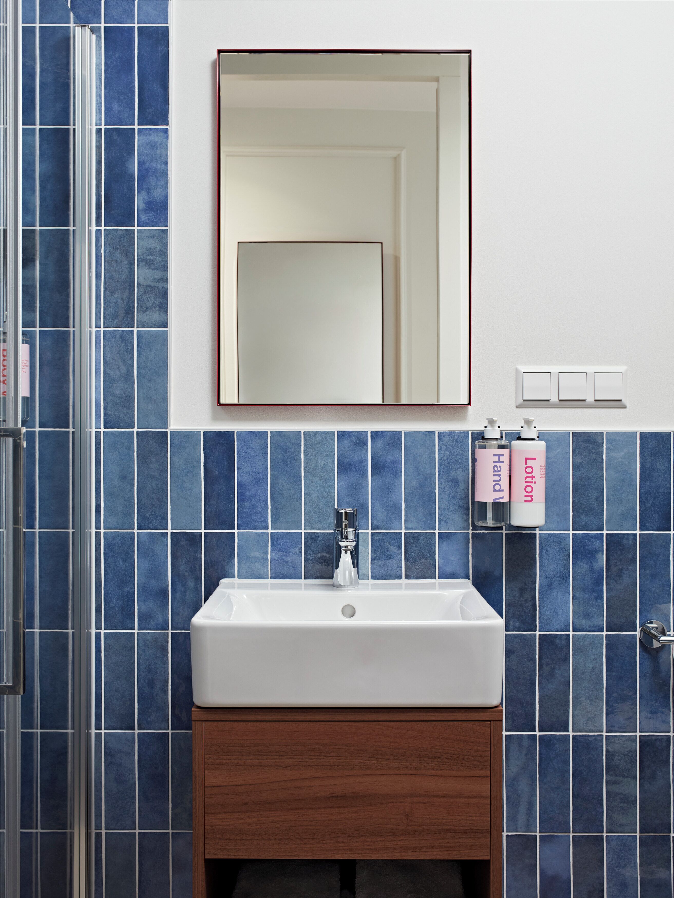 A bathroom with a white sink, a mirror, and blue tiles.