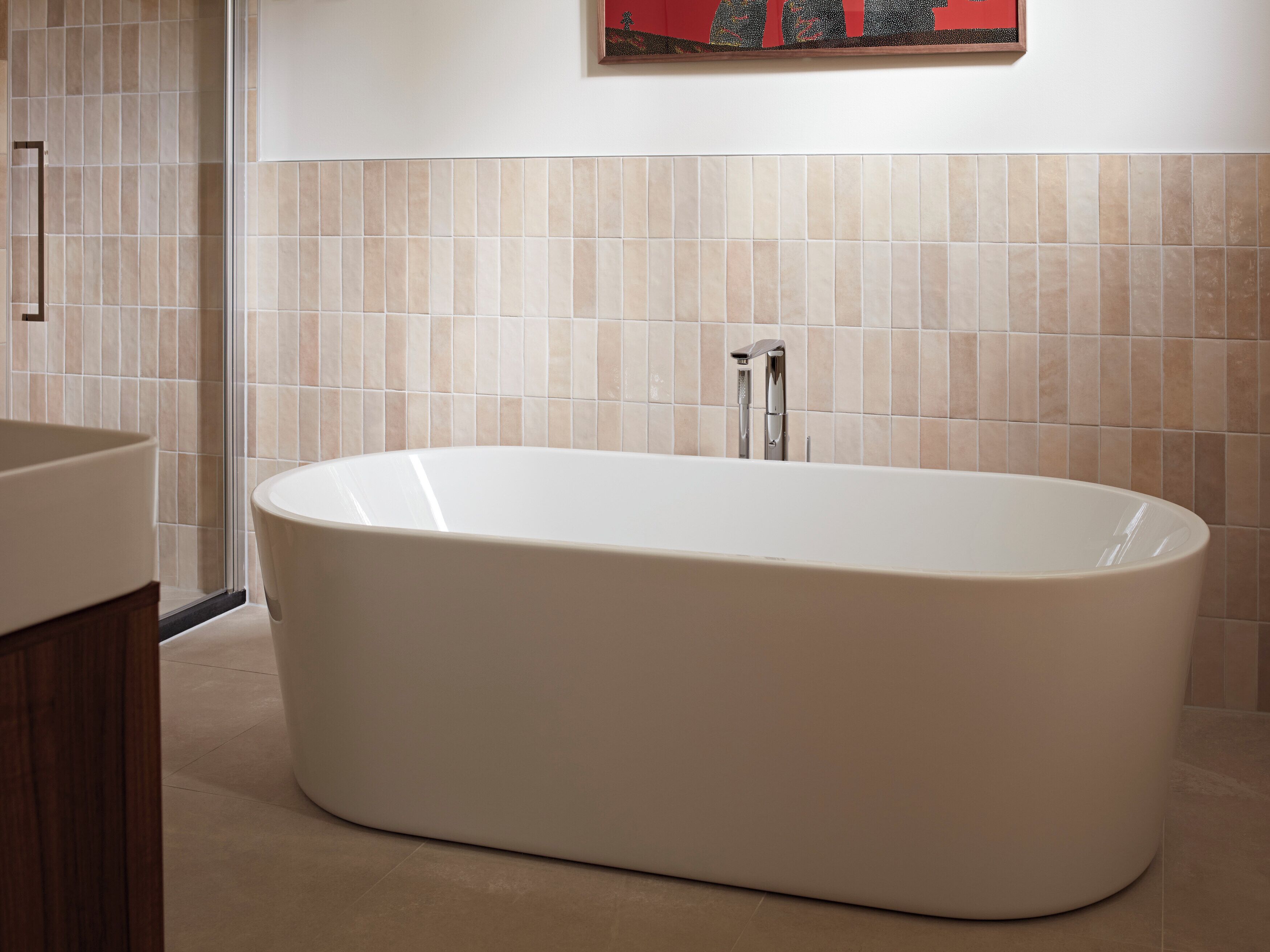 A modern bathroom with a freestanding bathtub, a shower area, and a tiled wall.