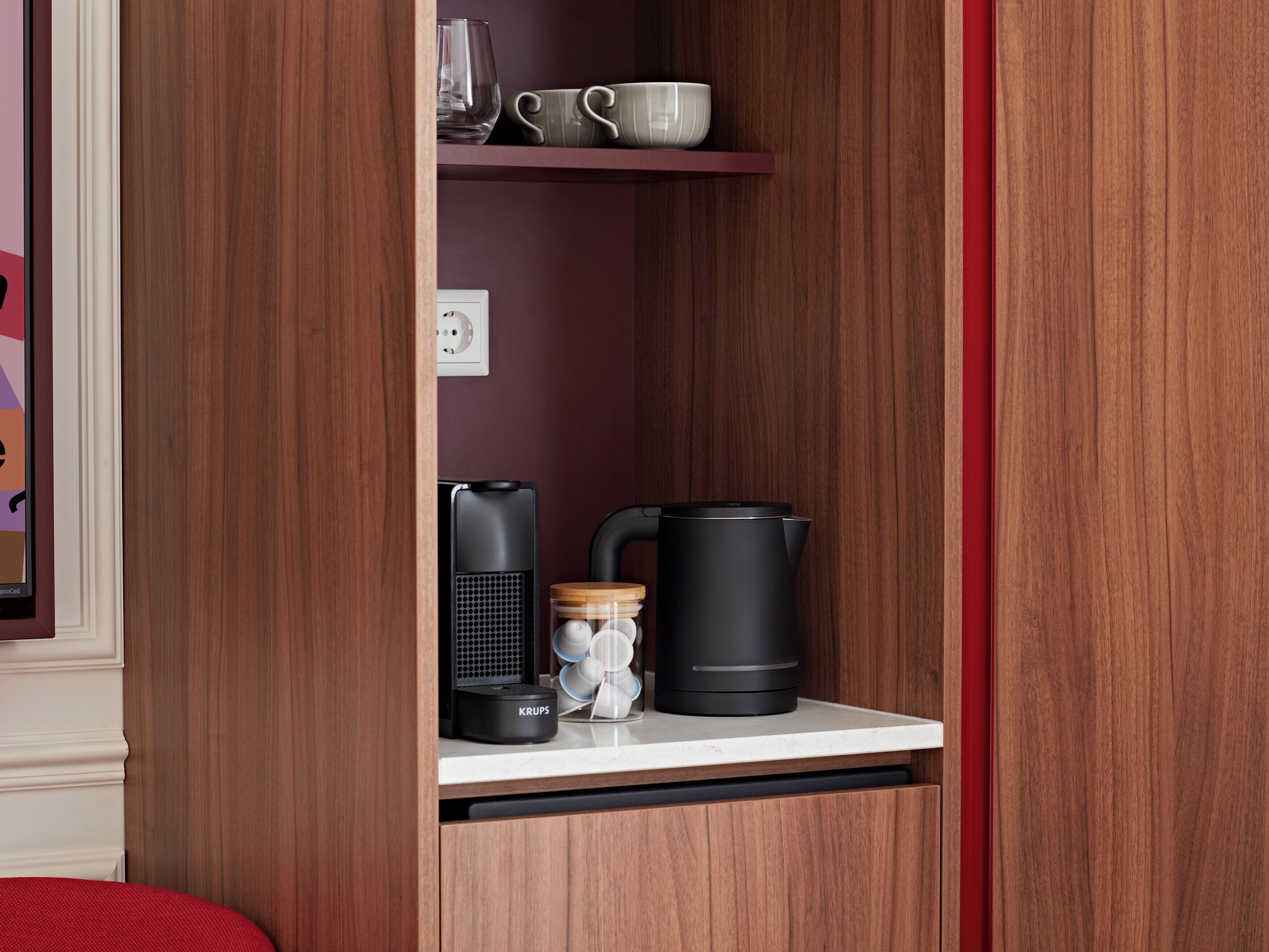 Eine Küchenzeile mit einer Kaffeemaschine, einem Wasserkocher und einem Einmachglas auf einer Arbeitsfläche.