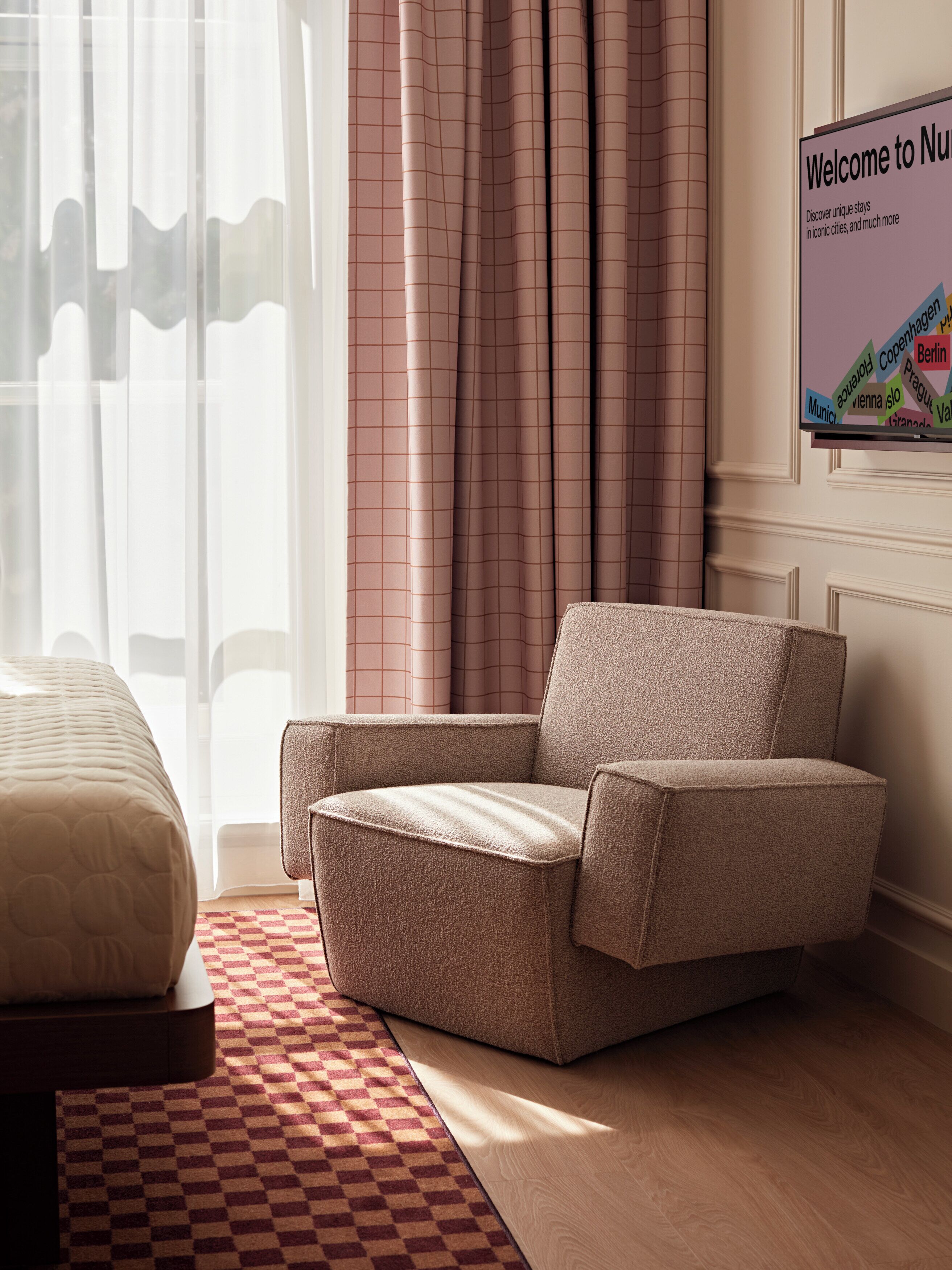 Una habitación de hotel con una cama, una silla, un tapete de cuadros y cortinas.