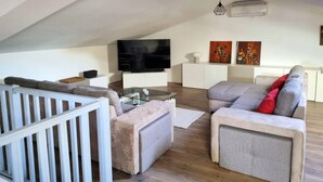 A modern living room with a flat-screen TV, grey sofas, a glass coffee table, and artwork on the walls. - Le Clos du Cornier - Peace & quiet & private pool (Barjac)