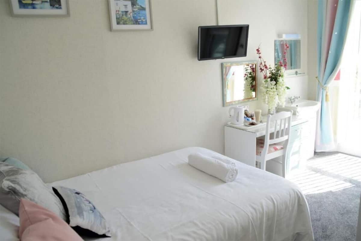 A hotel room with a bed, a desk, a chair, a television, and a window with curtains.