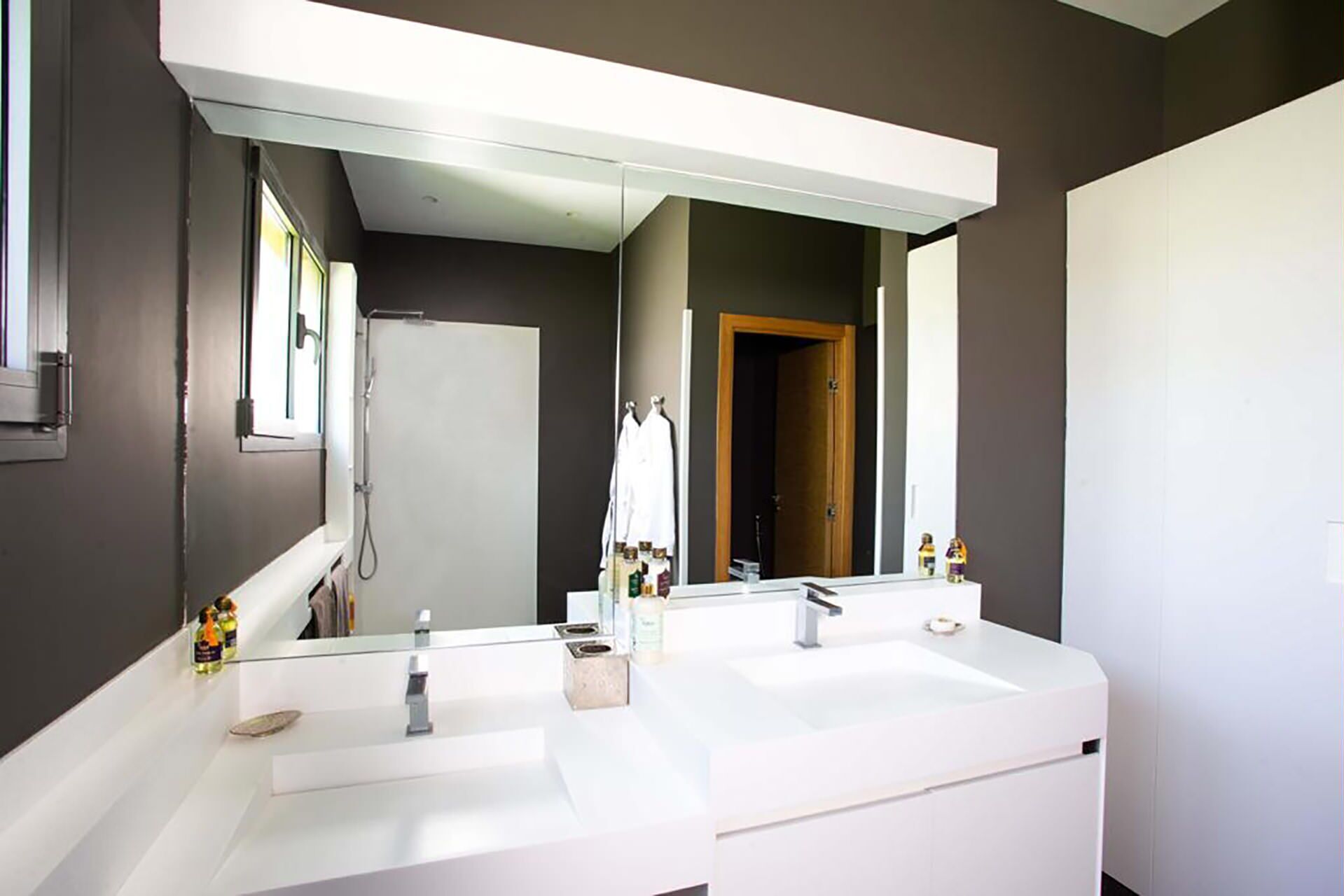 A modern bathroom with two sinks, a large mirror, and a shower.